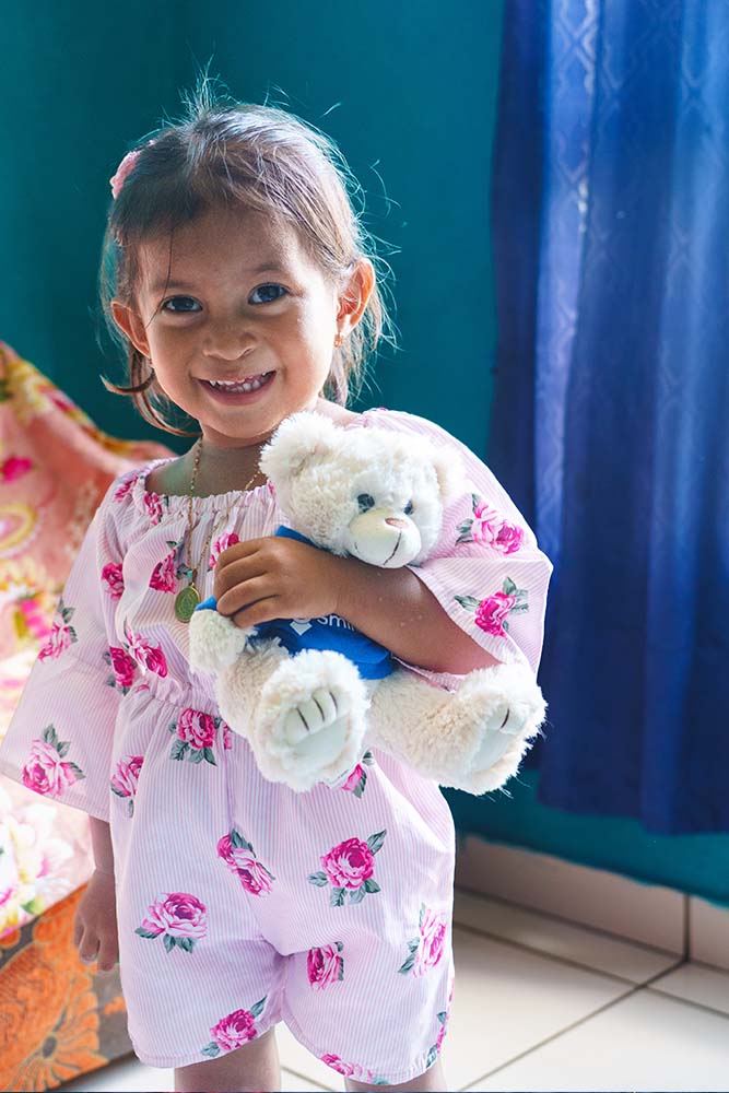 Elieth smiles and holds a stuffed animal