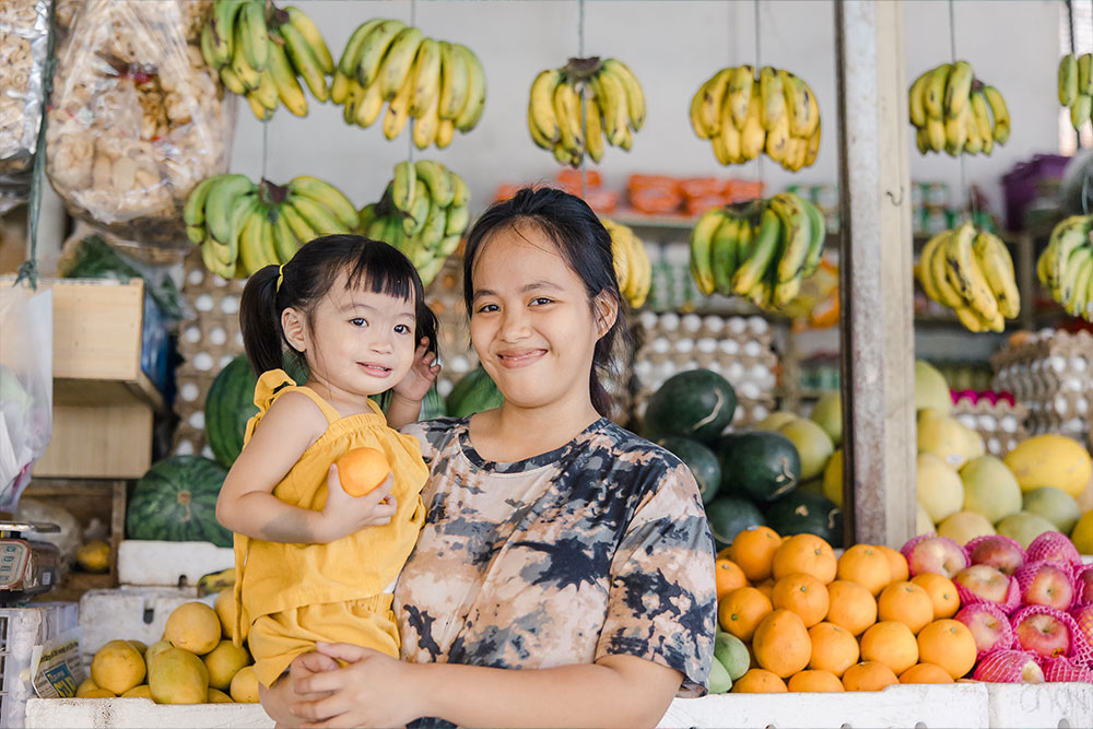 Danna holding Zabriena at her fruit stand