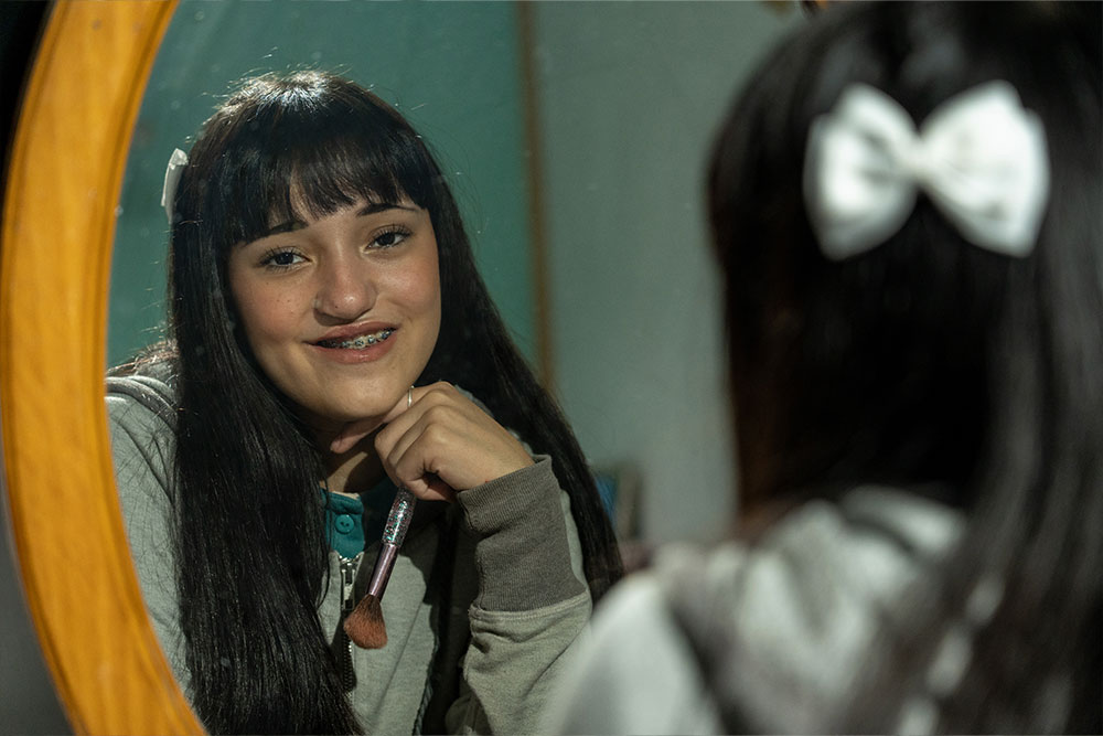 Camila looking in the mirror, putting on makeup