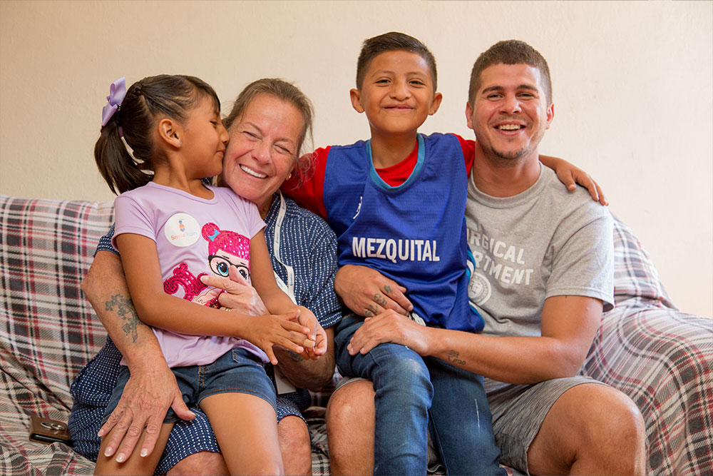 “Karen and James with Smile Train patients. She is getting a kiss from the one in her lap