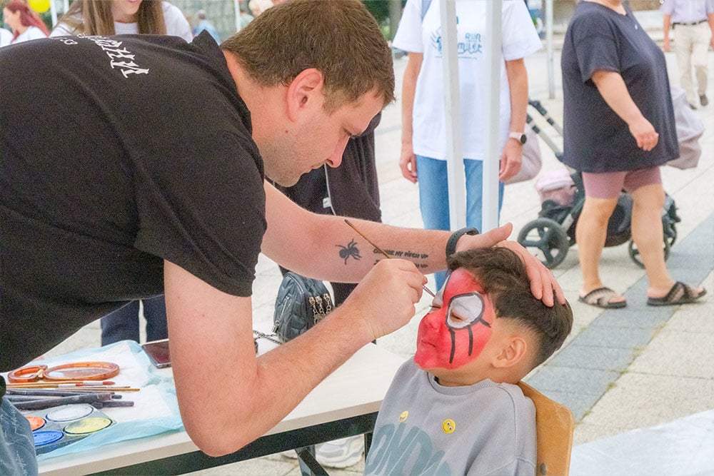 A child having his face painted like Spider-Man