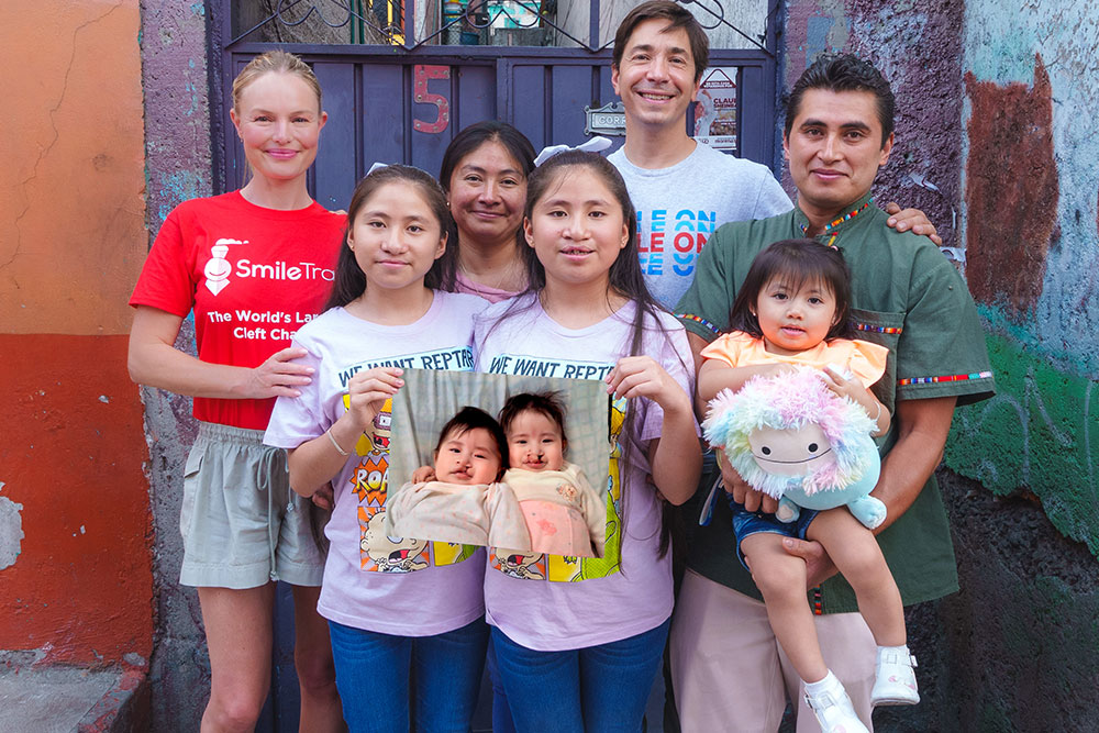 Justin Long and Kate Bosworth with Lizeth, Lizbeth, their baby sister, and their parents. The twins hold a picture of themselves as babies before cleft surgery