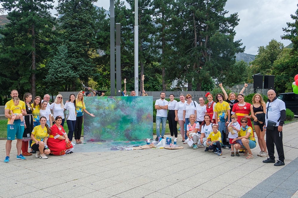Art Impact for Health participants stand before their finished collaborative painting project