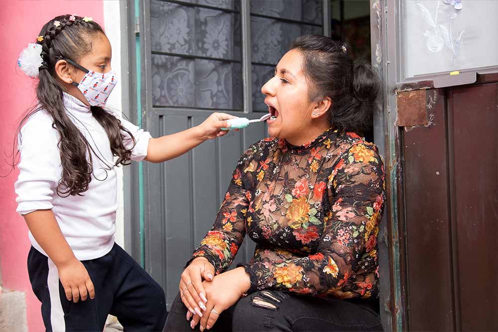 Ivanna wears a mask and plays dentist, inspecting Leticia’s mouth with a toy
