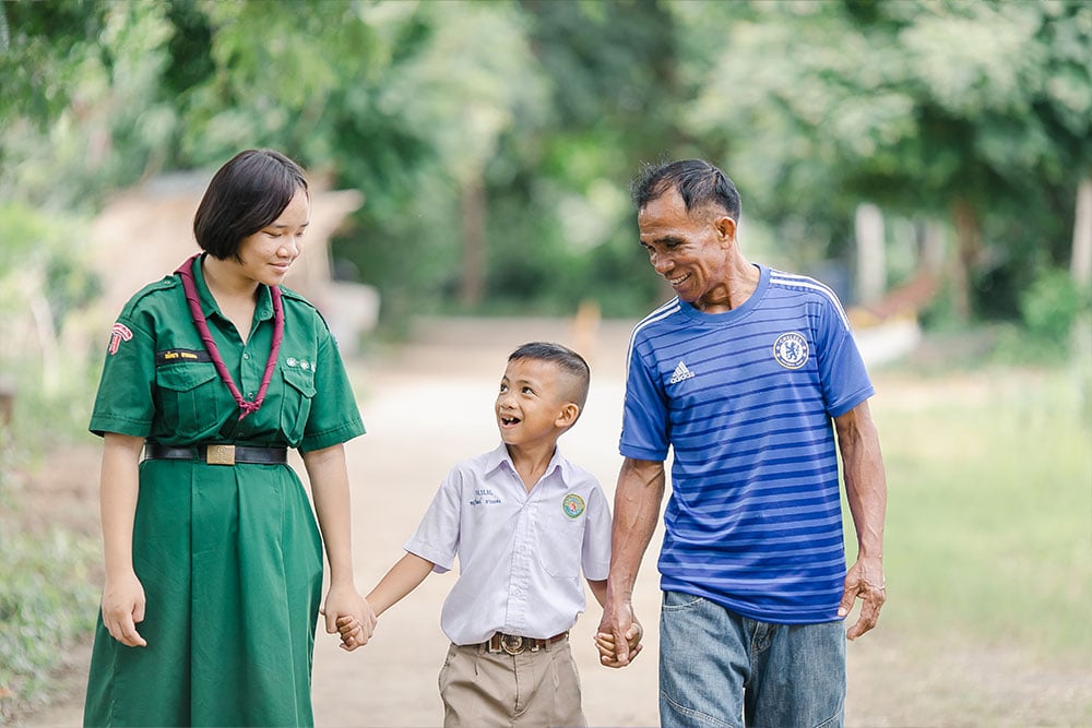 Aitya, Anuwat, and Chaipishek walking hand in hand, smiling