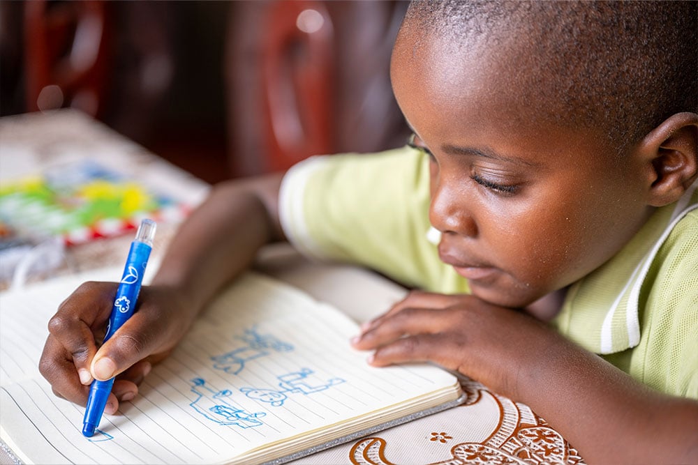 Wayne doodling in a notebook with a blue marker