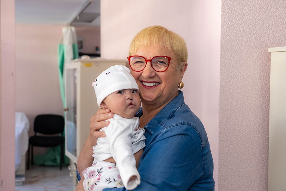 Lidia smiling, holding a baby before cleft surgery