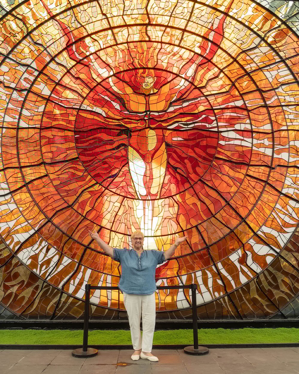 Lidia posing with a stained-glass mural at the Cosmovitral