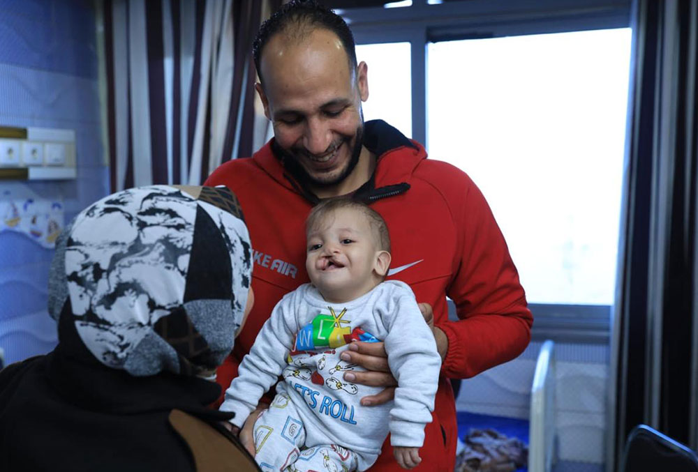 Mostafa smiling, holding Noah just before his cleft surgery