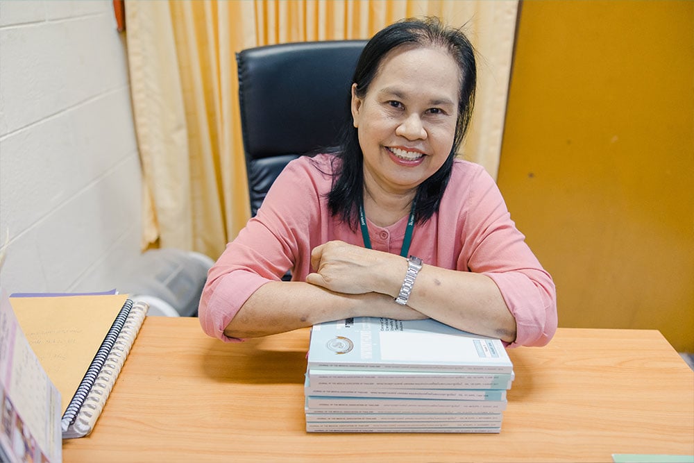 Suteera with a stack of medical journals