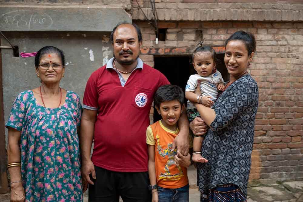 The entire family poses together outside and shares a smile: Aarosh’s grandmother, Gautham, Aarosh, as well as his baby sibling, who is held by Anjana