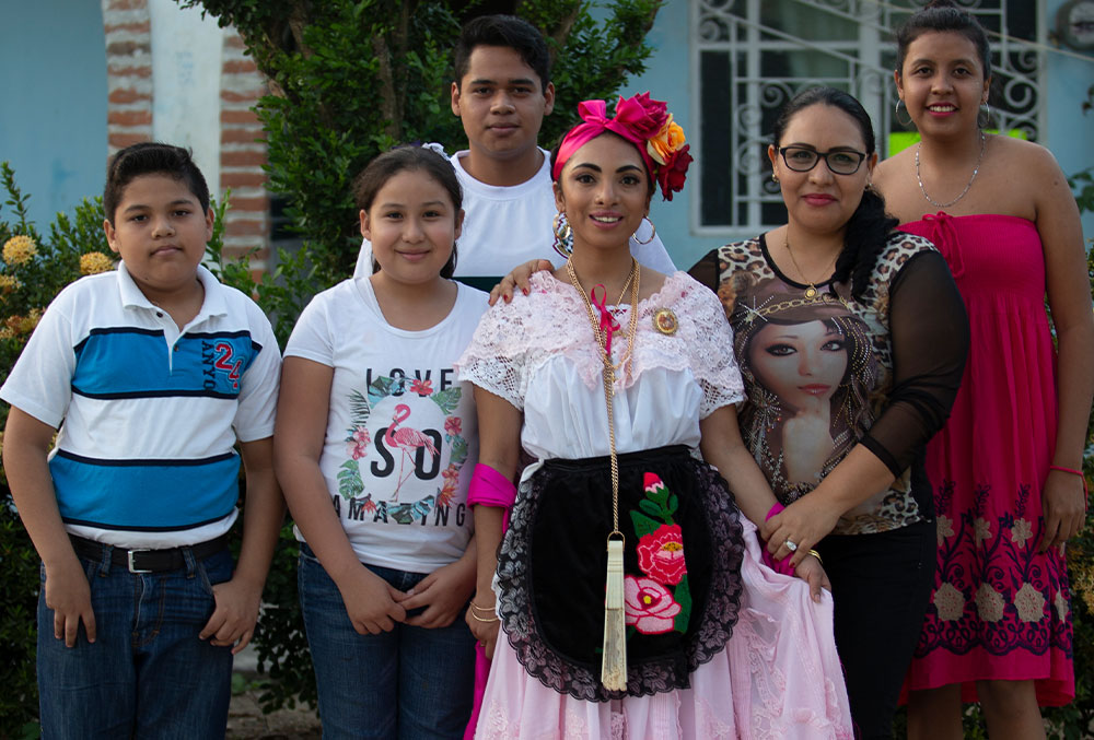Adahara dressed in traditional Mexican clothing poses with a group of neighbors after receiving cleft treatment