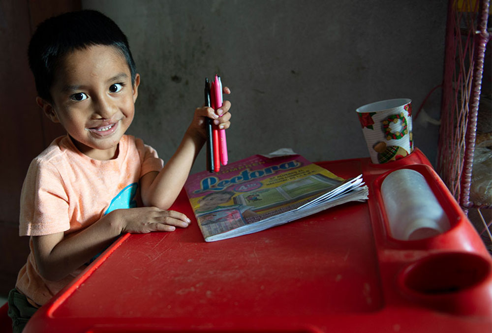 Anghelo drawing at his desk after free cleft treatment in Peru.