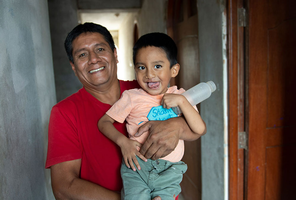 Jorje holds his son, Anghelo, as they both grin widely