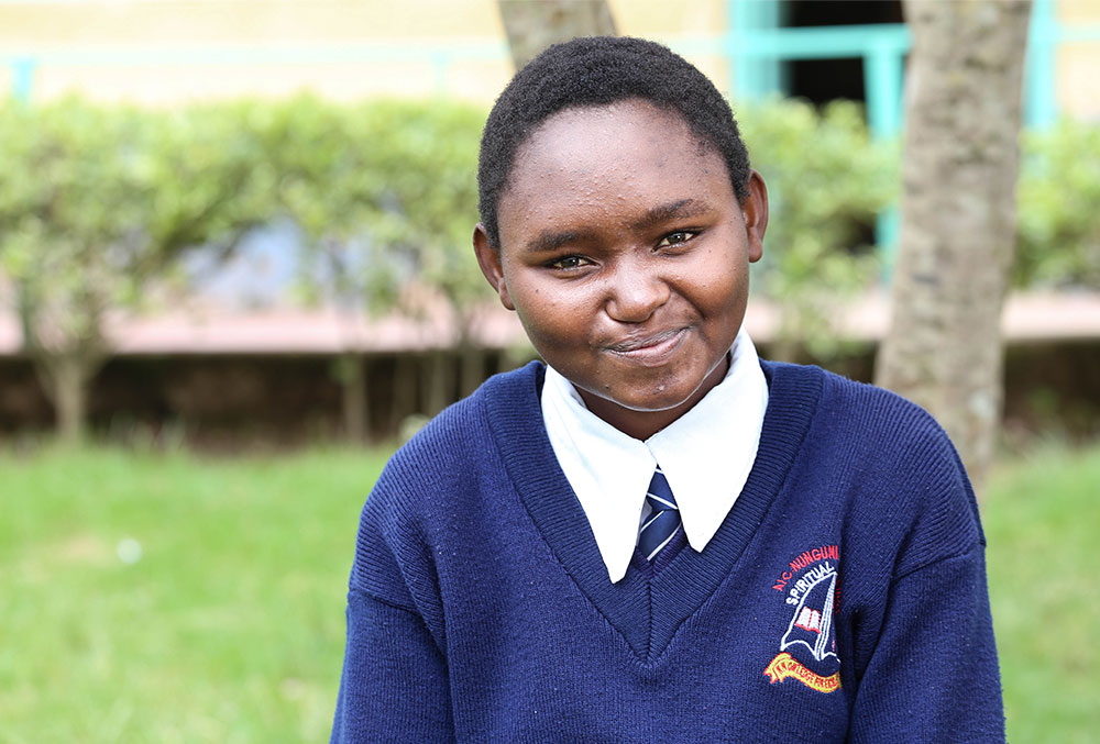 Damaris smiles in her school uniform after her free Smile Train-sponsored cleft surgery in Kenya