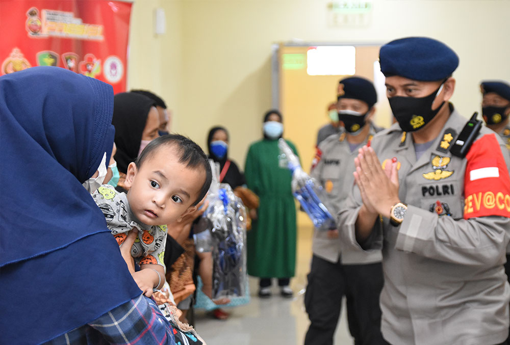 A mother brings her child with a cleft to an Indonesian police officer for free surgery from Smile Train