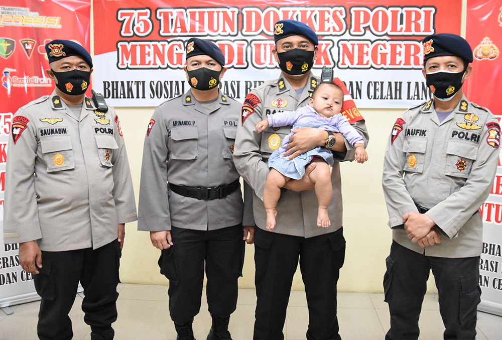 Four Indonesian police officers hold a baby before free Smile Train cleft surgery