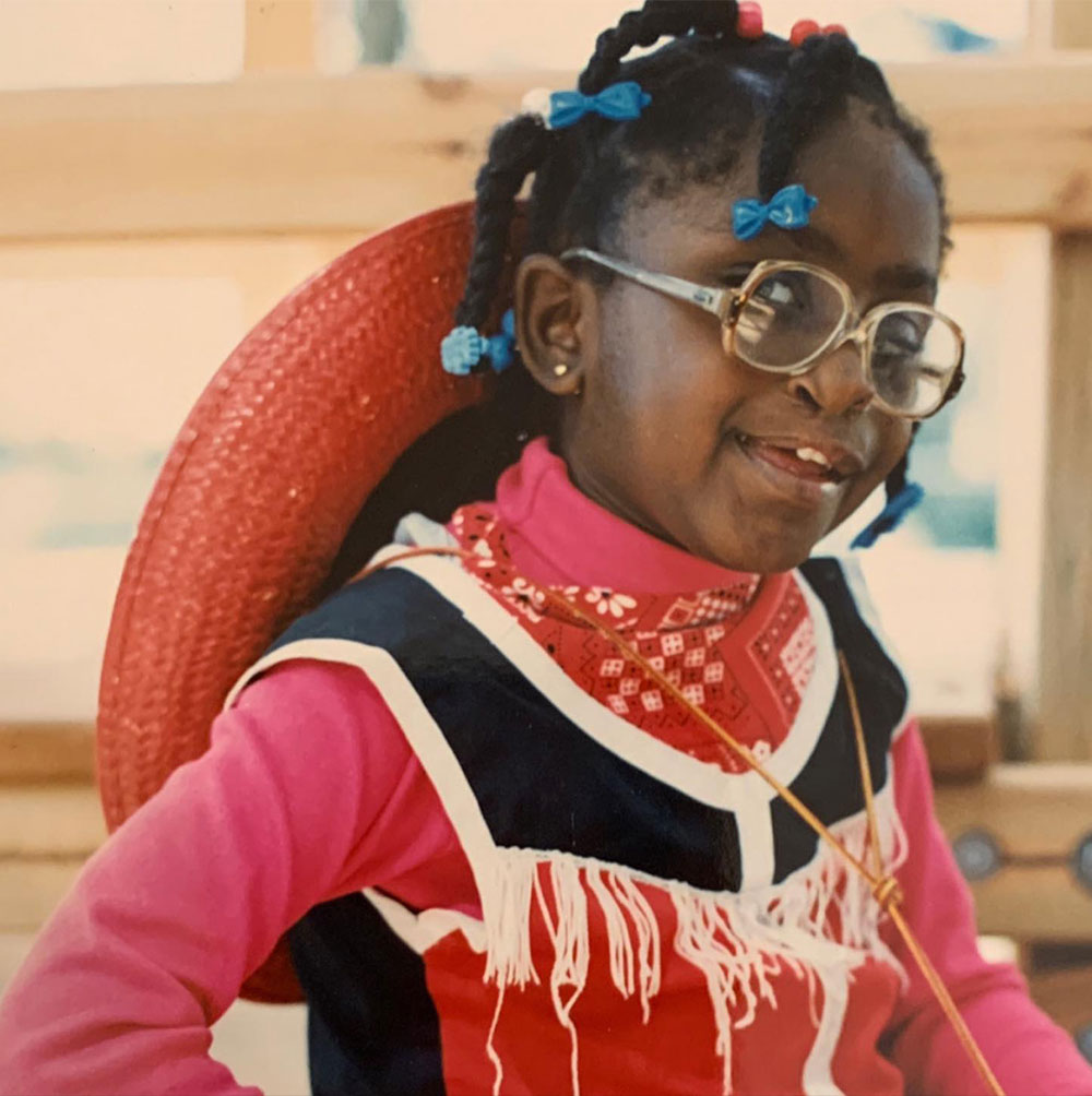 Iva Ballou as a girl with braids and glasses.