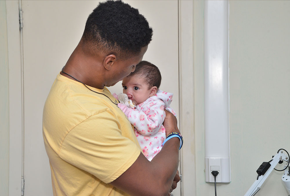 Kenyan Drake holds a baby with a cleft