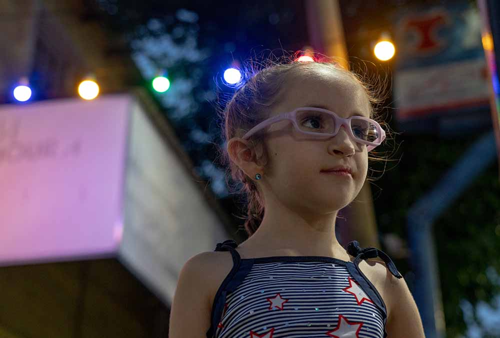 Mia standing in front of string of lights