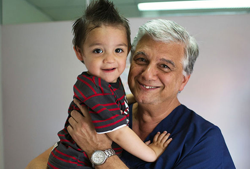 Smile Train partner surgeon holding a child with a cleft lip and palate after surgery