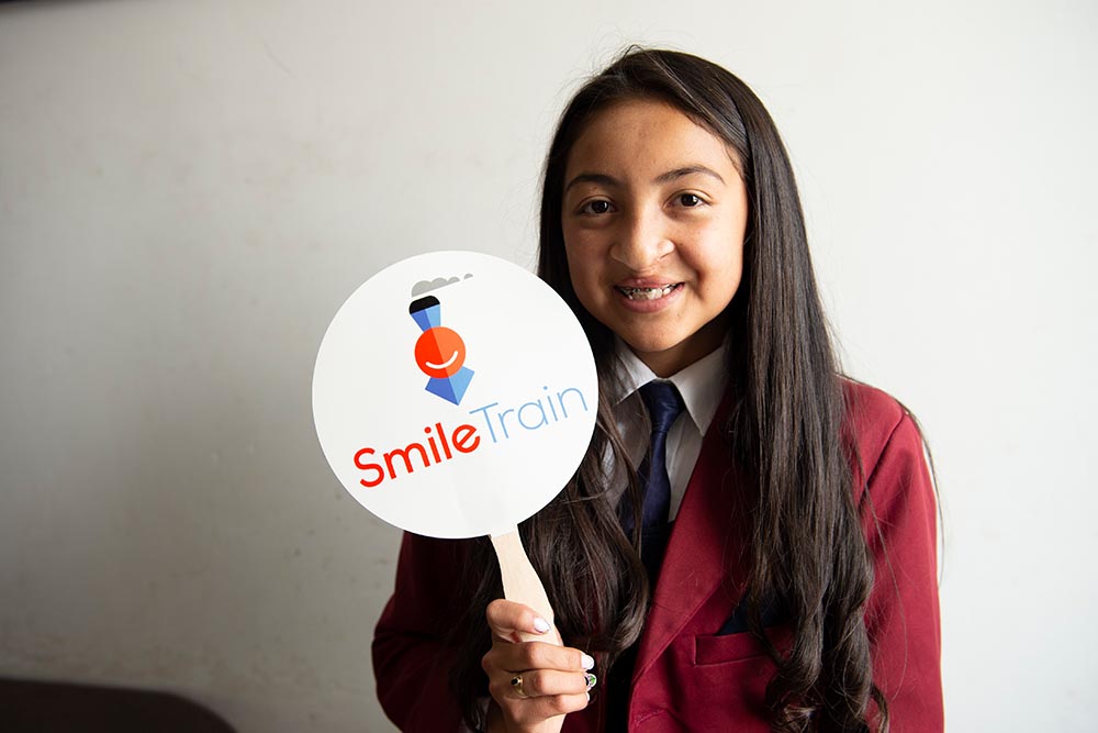 Monica holds up a Smile Train sign