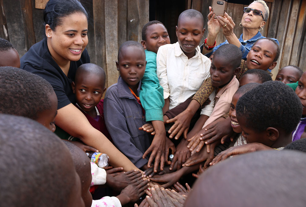 Nijha joins many Smile Train patients in Kenya joining their hands in the middle of a circle.