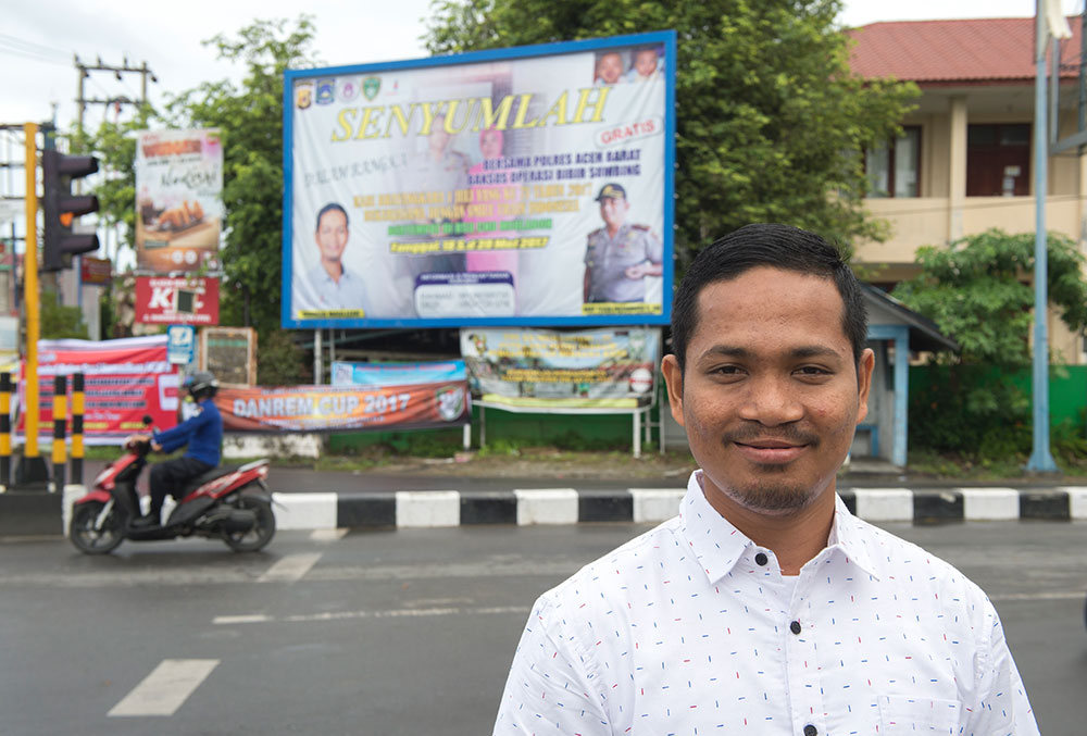 Rahmad stands before a Smile Train billboard