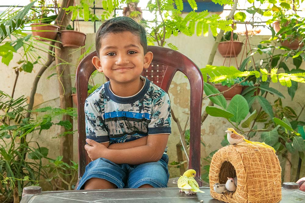 Saksham smiles with arms crossed behind his birds