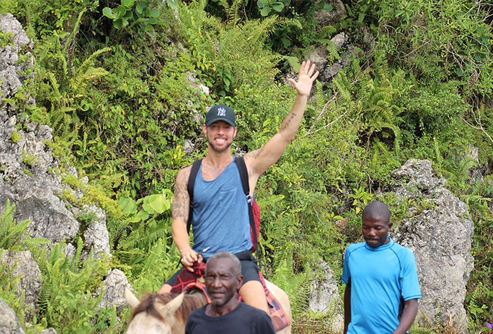 Troy waves while riding a horse in Haiti