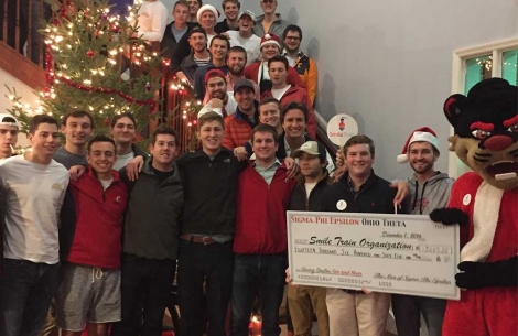 Large group pose with Smile Train donation check with school mascot