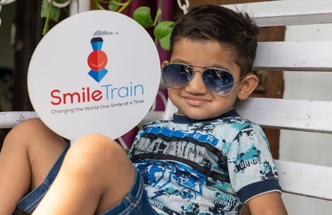 Child wearing sunglasses and Smile Train sign