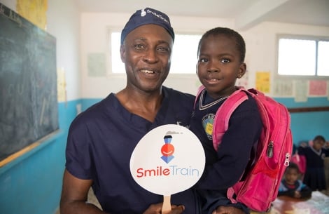 A cleft surgeon holds former patient in his arms