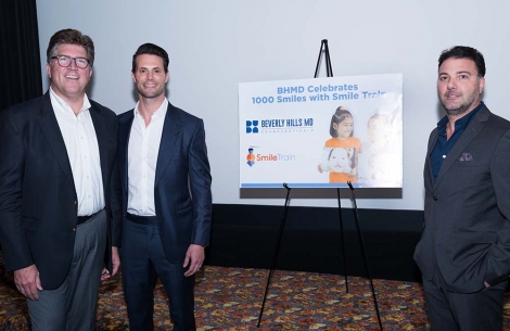 Group stands in front of movie screen for a fundraising event