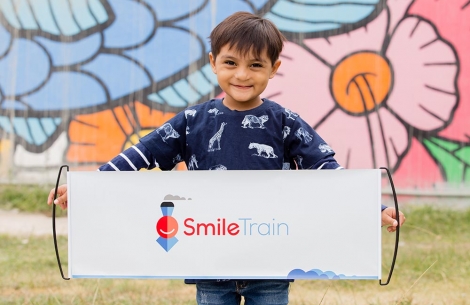 Boy holds up a Smile Train pull out banner