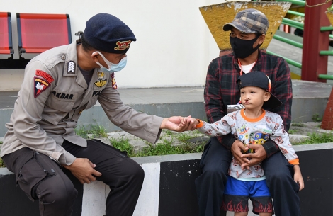 Indonesian police officer reaches out to a child with a cleft before his free Smile Train surgery.