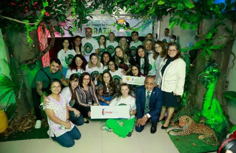 Art Impact Brazil staff and partners smiling and holding Smile Train signs