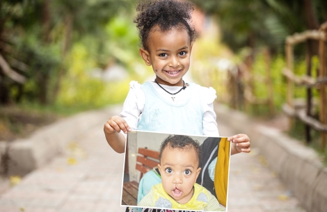 Makiba holding a picture of herself before cleft surgery