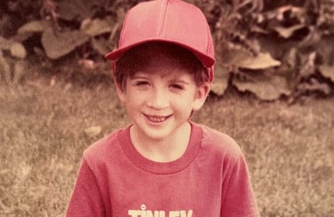 David kneeling in the grass in his baseball uniform