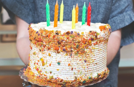 Decorated white birthday cake with colorful candles and sprinkles