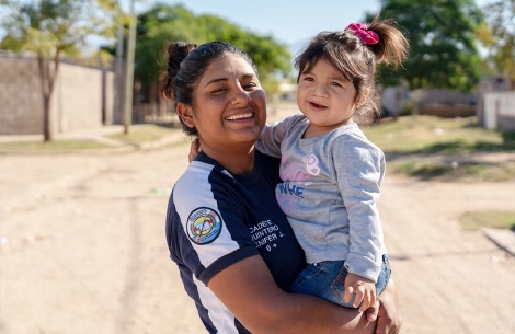 A smiling Jenifer holds Isabella in her arms