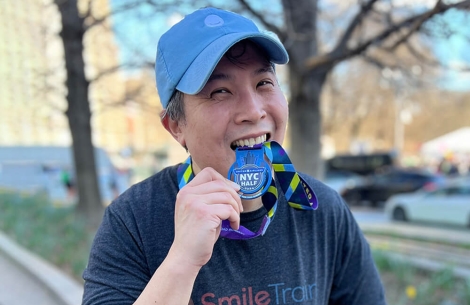 Albert Poon in Smile Train shirt holding NYC Half Marathon medal
