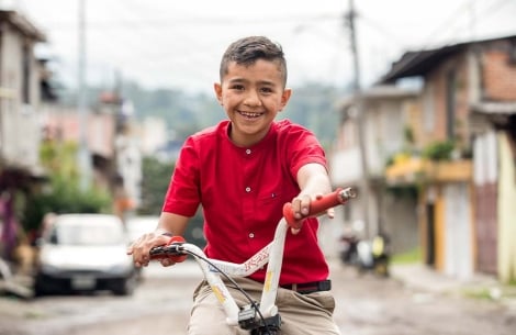 Jesus smiling and riding his bike after cleft surgery