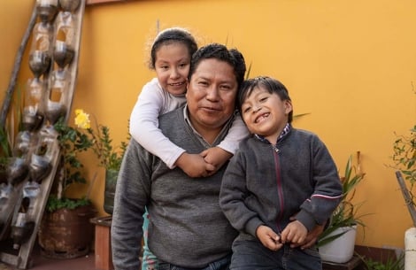 Rene smiles with his daughter, Anahí, and his son, Daniel. Anahí stands behind him and wraps her arms around him. Daniel smiles and nestles against his shoulder