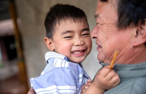 Gau grins as his grandpa holds him affectionately in his arms
