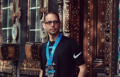 Aladdin Meriden standing against a colorful wall in the Old City of Damascus wearing his six World Marathon Majors medals