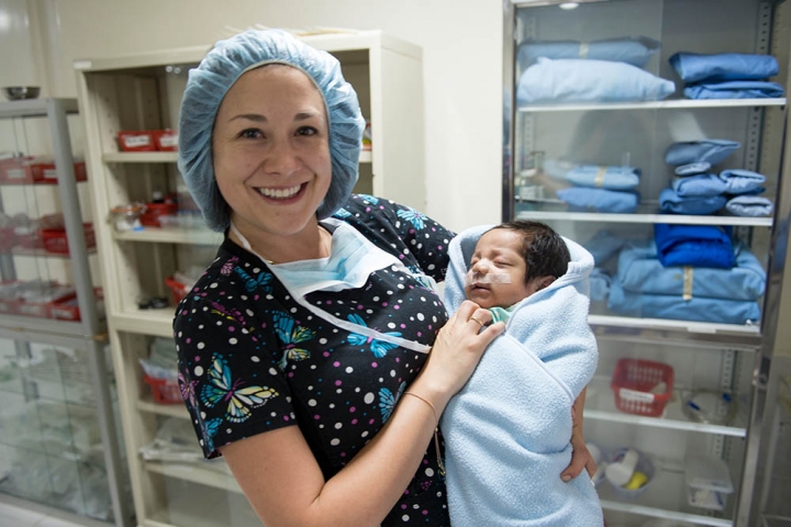 Doctor holds baby after cleft surgery