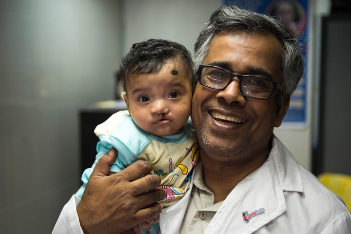A surgeon in Bangladesh holds a child with cleft