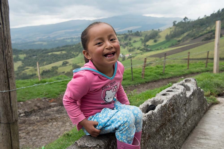 girl sits on cinder blocks with a big smile