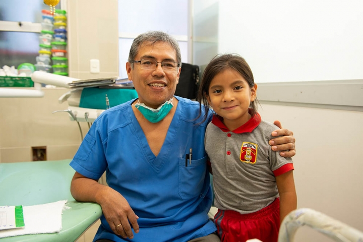 Dr Meza with his arm around a dental patient